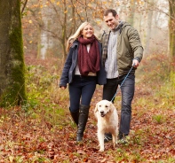 Mann und Frau mit Hund spazieren im Wald