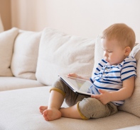 Kleinkind mit Tablet auf Sofa