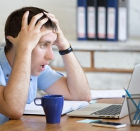 Junger Mann schockiert vor dem Laptop