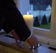 Bundesprsident Steinmeier stellt eine Kerze in ein Fenster von Schloss Bellevue.